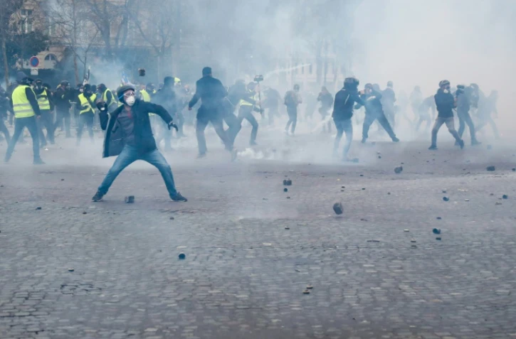 Un manifestant jette un pavé vers les forces de l'ordre près de l'Arc de triomphe à Paris le 16 mars 2019