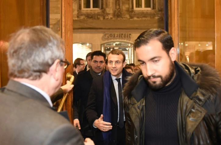 Photo en date du 13 décembre 2016 montrant Emmanuel Macron (C), à l'époque candidat à la présidentielle, précédé par son garde du corps Alexandre Benalla (D), dans une librairie de Bordeaux