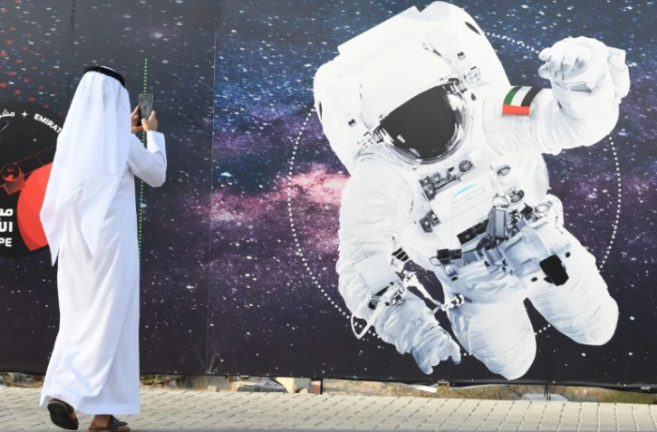 Un passant photographie l'image d'un astronaute dont le vêtement porte le drapeau émirati, devant le centre spatial Mohammed Bin Rashid à Dubaï, le 25 septembre 2019