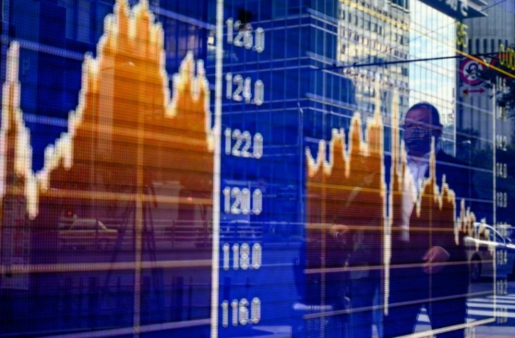 Des piétons passent devant les variations de la Bourse de Tokyo, le 6 novembre 2020