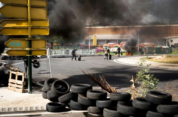 Militants de l'Union générale des travailleurs de Guadeloupe, faisant rouler des pneus pour installer un barrage à Perrin Les Abymes, en Guadeloupe, le 17 novembre 2021