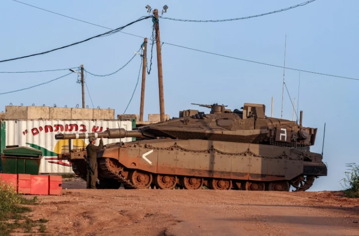 Un soldat israélien à côté d'un char de combat Merkava Mark IV le long de la frontière nord avec le Liban, à proximité du village de Shtula, le 6 avril 2023
