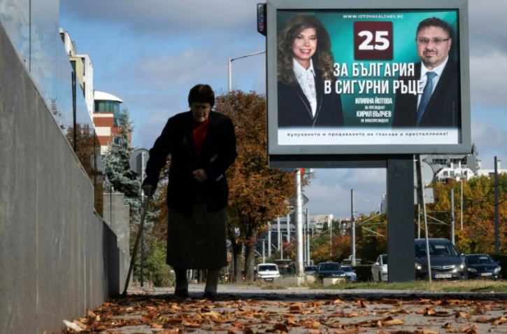 Une personne marche devant une affiche électorale de la présidente sortante de Bulgarie, Iliana Iotova, et de son vice-président candidat Kiril Valchev, à Sofia, le 23 octobre 2026