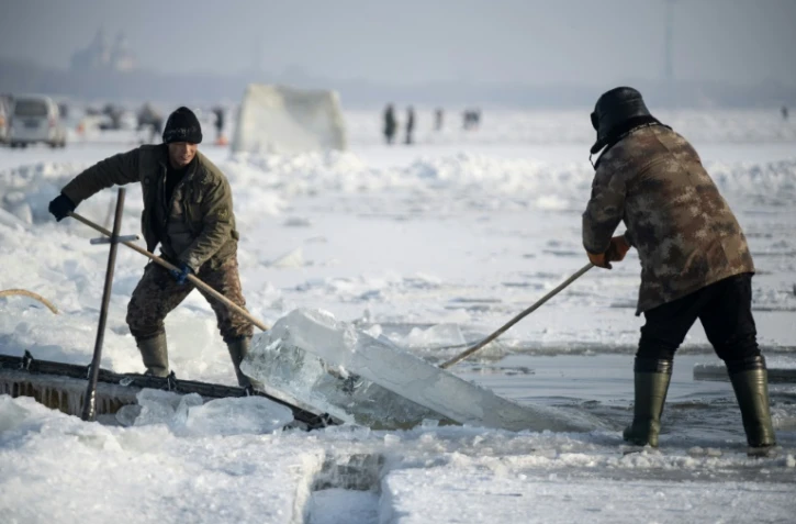 Des travailleurs sortent un bloc de glace de la rivière Songhua, le 12 décembre 2019 à Harbin, en Chine