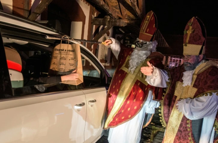 Des artistes du cirque Cirk La Putyka, déguisés en Saint Nicholas, distribuent des cadeaux aux enfants en voiture le 5 décembre 2020 à Prague