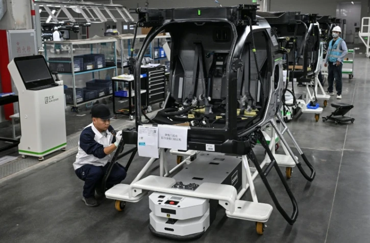 Des employés travaillent sur une chaîne de montage pour la voiture volante électrique "Land Aircraft Carrier" dans une usine de la filiale Aridge de Xpeng à Guangzhou, dans le sud de la Chine, le 6 novembre 2025