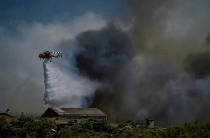 Un hélicoptère largue une cargaison d'eau sur un feu de forêt à Keratea, près d'Athènes, le 30 juin 2024 en Grèce