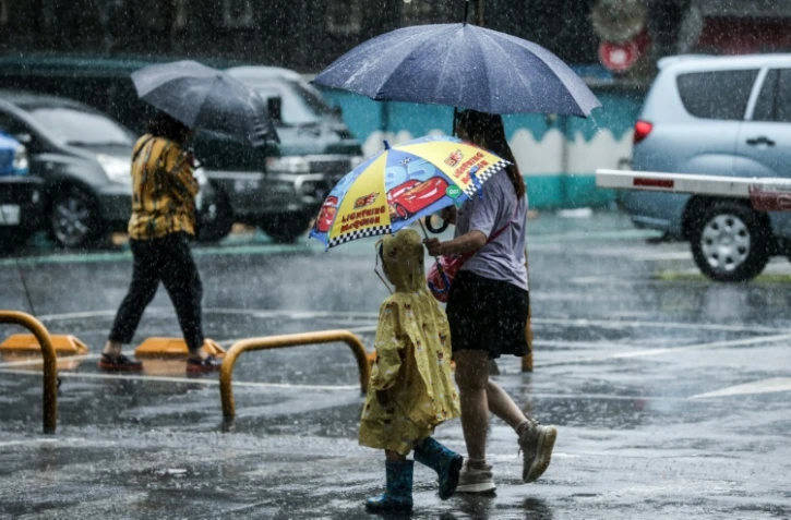 Des personnes tiennent des parapluies dans la rue sous la pluie à Keelung après le passage du typhon Haikui à Taïwan, le 4 septembre 2023