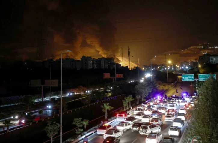 Circulation dense sur une autoroute à Téhéran alors qu'un incendie fait rage à proximité dans un dépôt de carburant, le 15 juin 2025