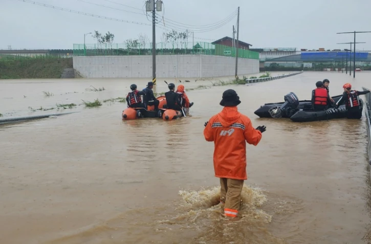 Des secouristes sud-coréens à la recherche de survivants le long d'une route inondée menant à un tunnel souterrain où 19 voitures ont été piégées par les eaux de crue après de fortes pluies à Cheongju, en Corée du Sud, le 15 juillet 2023