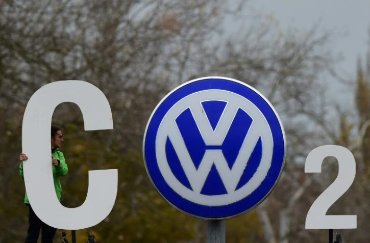 Montage réalisé par un militant de Greenpeace autour du logo du constructeur automobile allemand sur la carosserie d'une voiture VW garée devant le quartier général de Volkswagen, à Wolfsburg le 9 novembre 2015
