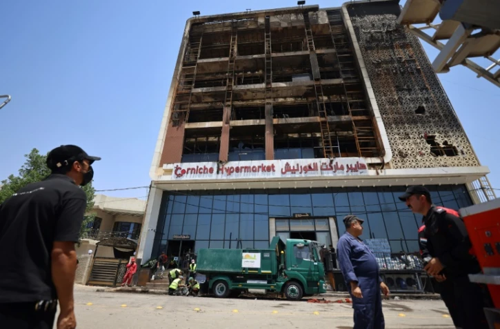 Opération de nettoyage devant le bâtiment du centre commercial Hyper Mall ravagé par un incendie dans la nuit tuant plus de 60 personnes, le 17 juillet 2025 à Kut, dans l'est de l'Irak