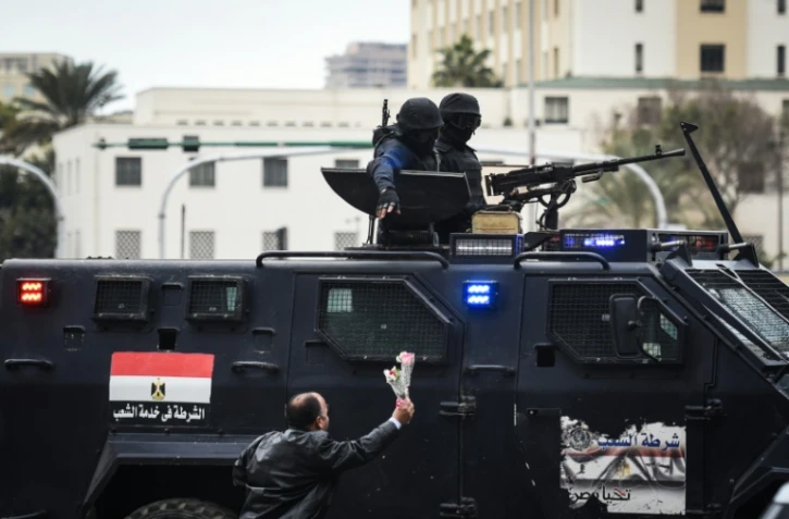 Un Egyptien tend des fleurs à des policiers des forces spéciales, sur la place Tahrir, au Caire, le 25 janvier 2016 