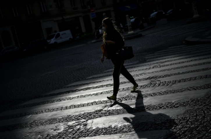Une femme traverse une rue déserte, le 21 avril 2020 à Paris, pendant le confinement instauré en France pour lutter contre l'épidémie de coronavirus