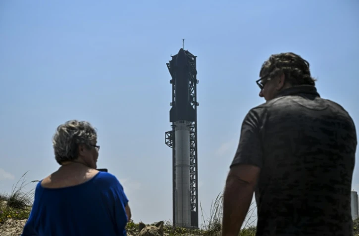 Des personnes observent la fusée Starship sur la rampe de lancement avant son quatrième vol d'essai à la base spatiale Starbase de SpaceX à Boca Chica, au Texas, le 5 juin 2024