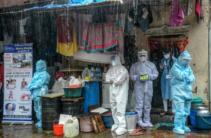 Des soignants en combinaison de protection s'abritent de la pluie à Bombay (Inde) le 12 août 2020