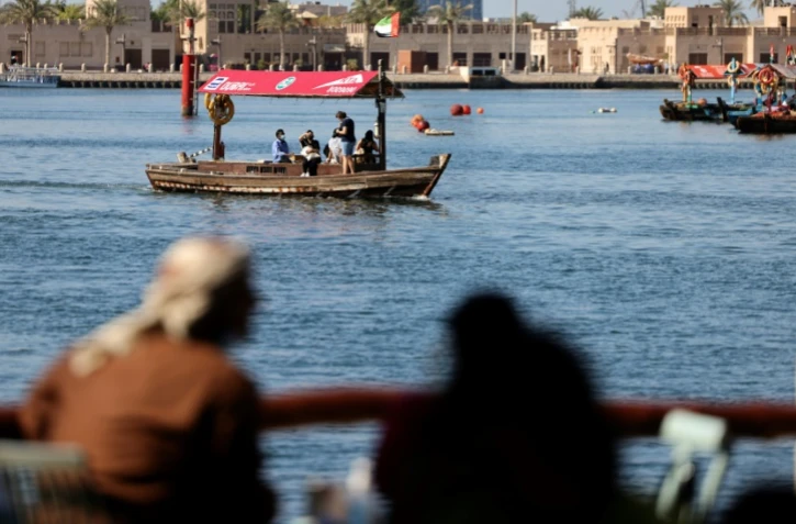 Des Emiratis regardent des bateaux transportant des touristes près du vieux quartier de Dubaï, aux Emirats arabe unis, le 6 janvier 2021