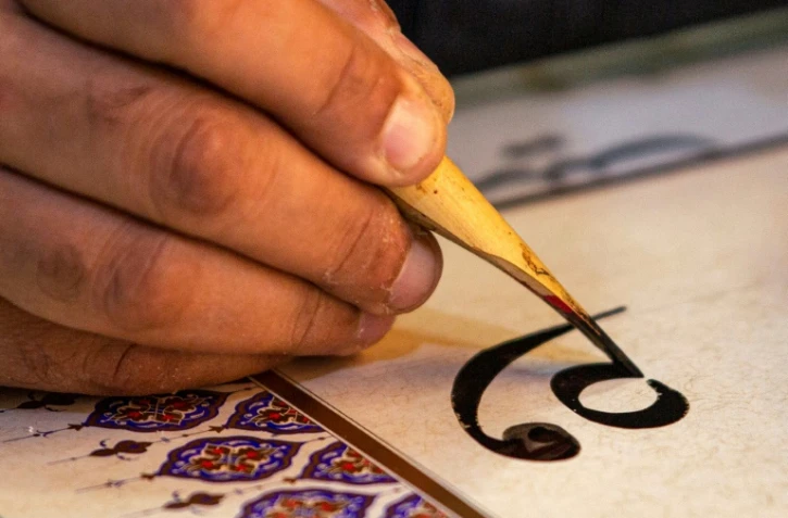 Le calligraphe irakien Wael al-Ramadan, utilise un calame pour calligraphier dans le style "Diwani" dans son atelier à Bassora, dans le sud de l'Irak, le 19 décembre 2021