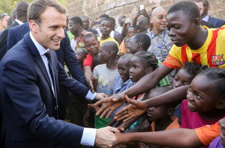 Emmanuel Macron serrant les mains d'enfants burkinabés, après la visite d'une école de Ouagadougou, le 28 novembre 2017