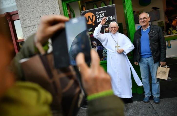 Des touristes se prennent en photo avec une statue de cire représentant le pape François à Dublin, le 24 août 2018