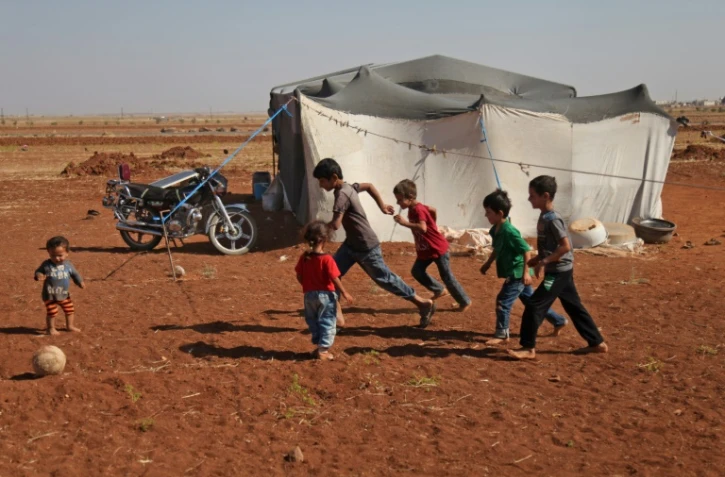 Des enfants syriens jouent à la balle devant une tente dans un camp de déplacés près du village de Surman dans la province d'Idleb en Syrie, le 5 septembre 2018 