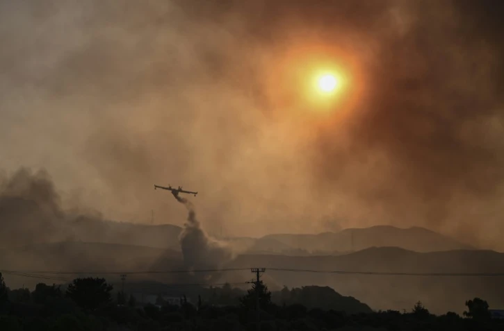 Un avion Canadair largue sa cargaison d'eau sur un incendie de forêt à Gennadi, sur l'île de Rhodes, le 25 juillet 2023 en Grèce