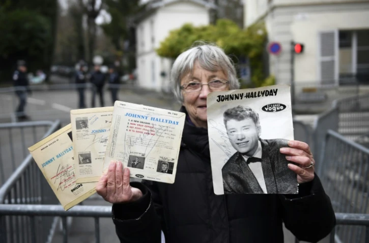 Une fan montre les autographes de Johnny devant la maison du chanteur à Marnes-la-Coquette, le 6 décembre 2017