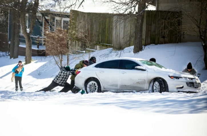 Des habitants d'Austin, au Texas, poussent une voiture dans la neige le 15 février