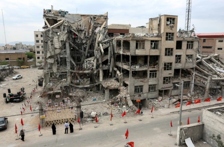 Des habitants devant un immeuble résidentiel détruit par une frappe aérienne américano-israélienne à Téhéran, le 13 avril 2026