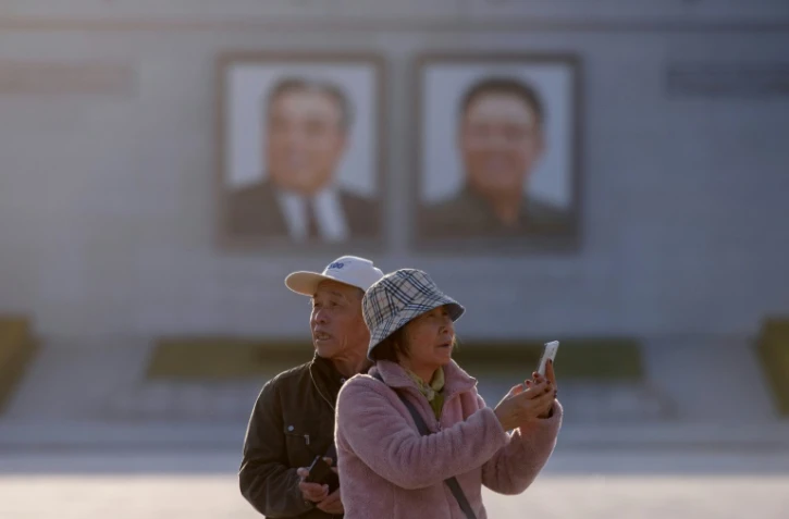 Des touristes chinois prennent des photos sur la place Kim Il Sung à Pyongyang, le 14 avril 2019 en Corée du Nord