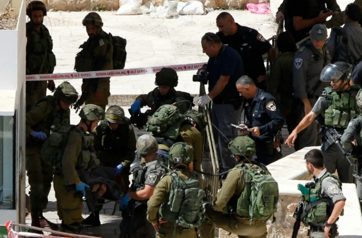 Des membres des forces de sécurité israéliennes évacuent un des Palestiniens abattus après une attaque au couteau, le 19 septembre 2016, près du Tombeau des Patriarches, à Hébron