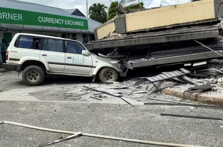 Photo publiée par Michael Thompson, habitant du Vanuatu, montrant des personnes en train d'inspecter les décombres d'un bâtiment détruit par un puissant séisme, à Port-Vila, le 17 décembre 2024