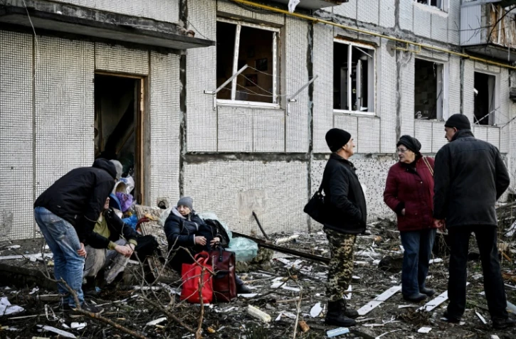Des habitants à l'extérieur d'un immeuble détruit par des bombardements, le 24 février 2022 à Tchouhouïv, dans l'est de l'Ukraine