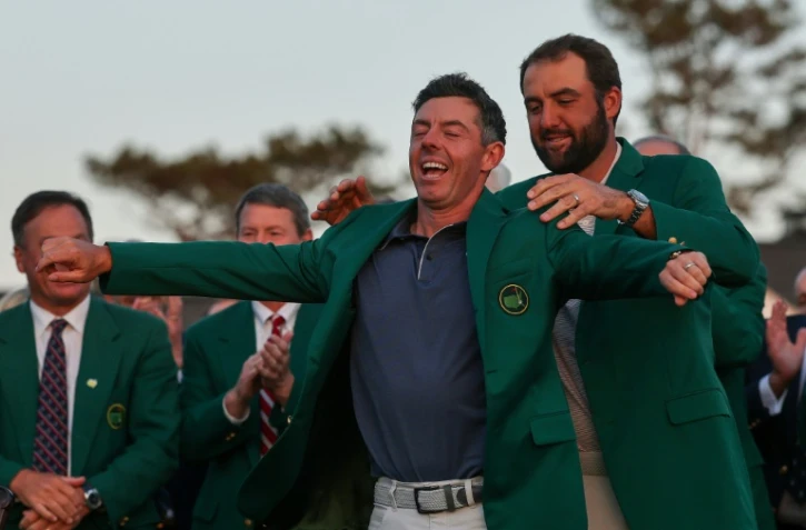 Le Nord-irlandais Rory McIlroy enfile la fameuse veste verte dévolue au vainqueur du Masters de golf d'Augusta, aux Etats-Unis, que lui remet le précédent tenant du titre Scottie Scheffler, le 13 avril 2025