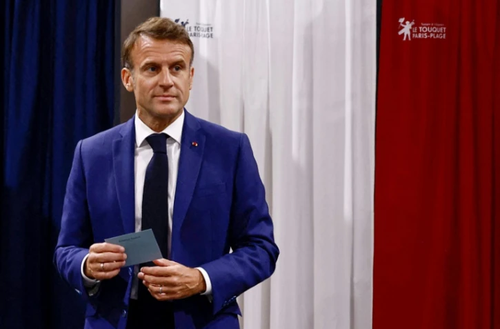 Le président Emmanuel Macron quitte l'isoloir dans un bureau du Touquet, dans le Pas-de-Calais, le 30 juin 2024