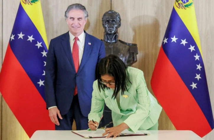 Photo diffusée par le bureau de presse de la présidence vénézuélienne montrant la présidente par intérim du Venezuela, Delcy Rodriguez (d), signant un document aux côtés du ministre américain à l'Intérieur, Doug Burgum, au palais présidentiel de Miraflores, le 5 mars 2026 à Caracas