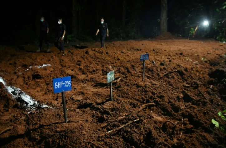 Des agents de police marchent à proximité de tombes de victimes non identifiées de la crue dévastatrice, le 30 août 2026 à Devghat au Népal
