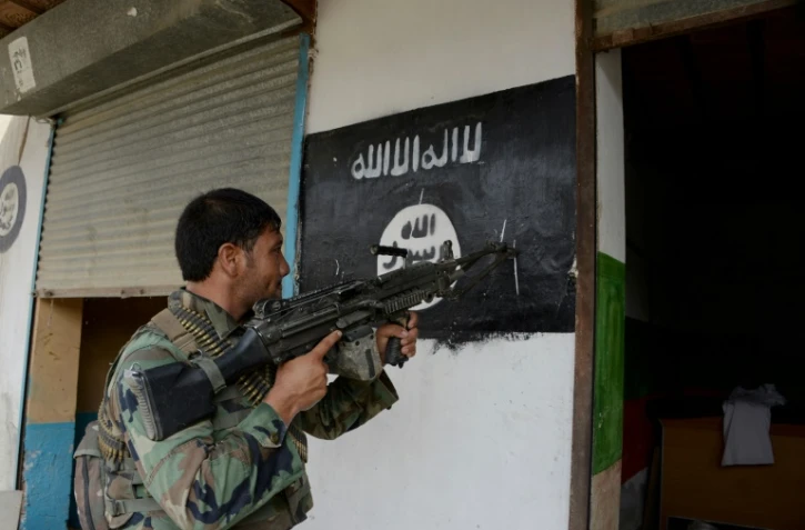 Un soldat de l'armée afghane pointe son arme sur un drapeau du groupe Etat islamique peint sur un mur à Kot, dans l'est de l'Afghanistan, le 26 juillet 2016