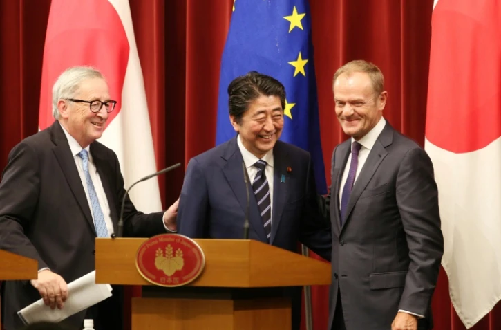 Le Premier ministre japonais Shinzo Abe (C), le président de la Commission européenne Jean-Claude Juncker (G) et le président du Conseil européen Donald Tusk (D) tout sourires après la signature d'un accord de libre-échange, à Tokyo le 17 juillet 2018