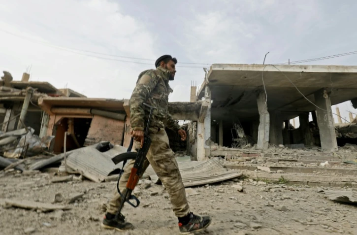 Un combattant des Forces démoctariques syriennes (FDS) passe devant un ancien bâtiment occupé par le groupe jihadiste Etat islamique (EI) dans le village de Hajine dans la province orientale syrienne de Deir Ezzor, le 27 janvier 2019 