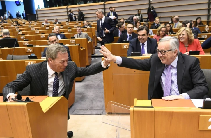 Le président de la Commission européeenne Jean-Claude Juncker (D) et l'eurodéputé britannique et fervent défenseur du Brexit Nigel Farage (G) font le geste du "high five" ("tape m'en cinq", pour encourager ou féliciter) au Parlement européen, à Bruxelles, le 2 mai 2018