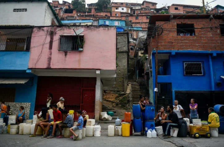 Des habitants du quartier de Petare font la queue avec des bidons et des seaux pour s'approvisionner en eau, le 1er avril 2019 à Caracas, au Venezuela