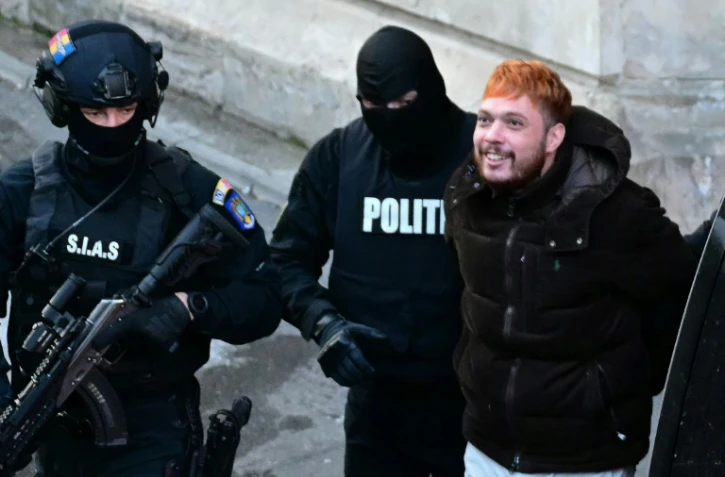 Le trafiquant de drogue français Mohamed Amra (c) escorté par des policiers hors de la Cour d'appel de Bucarest, le 23 février 2025, au lendemain de son arrestation en Roumanie