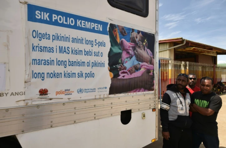 De hommes attendent devant un centre moblie de vaccination dans une rue de Mount Hagen en Papouasie-Nouvelle-Guinée, le 22 novembre 2018