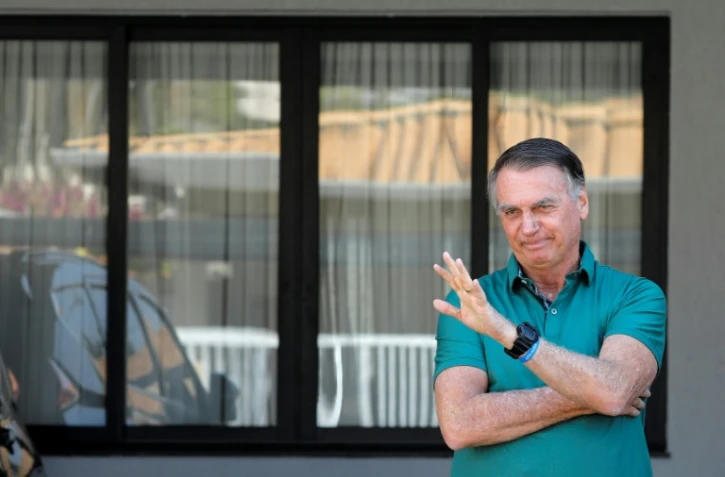 L'ex-président brésilien Jair Bolsonaro fait un salut de la main, devant sa résidence à Brasilia, le 11 septembre 2025