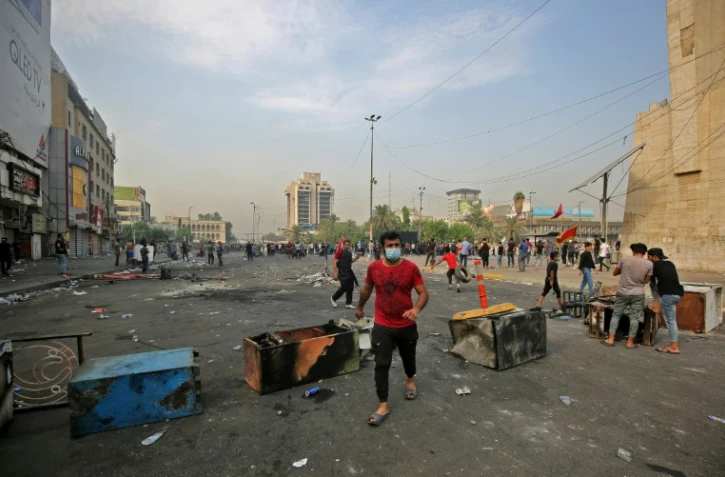 Un homme marche près de barricades érigées par des manifestants à Bagdad le 3 octobre 2019 où se déroulent des rassemblements contre la corruption et le chômage

