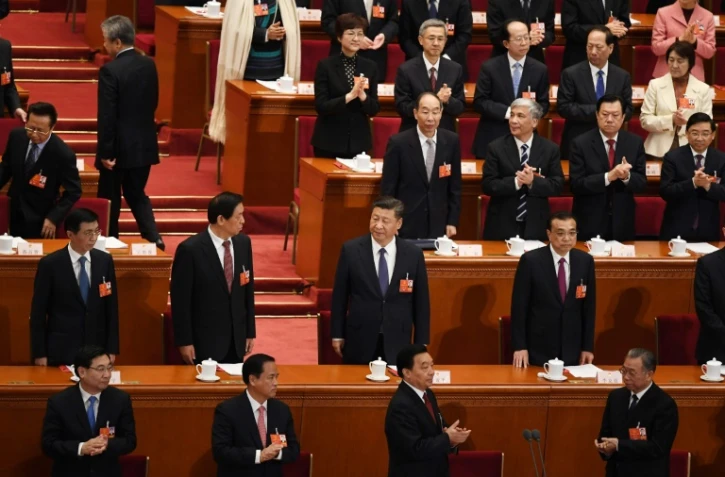 Le président chinois Xi Jinping (c) et le Premier ministre Li Keqiang (d, 2è rang), lors d'un vote sur le changement de la Constitution à l'Assemblée nationale populaire à Pekin, le 11 mars 2018