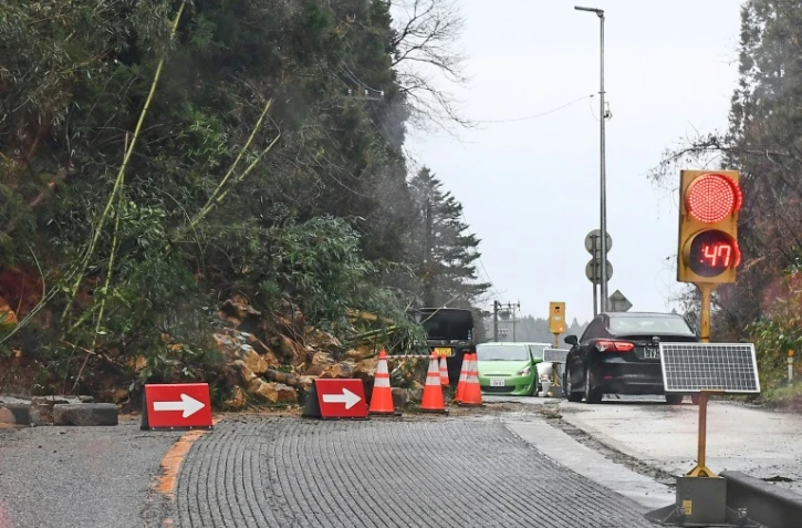 Des panneaux et des cônes de signalisation dirigent les automobilistes après qu'un tronçon de route a été partiellement bloqué à la suite d'un glissement de terrain dans la ville de Nanao, préfecture d'Ishikawa, le 3 janvier 2024