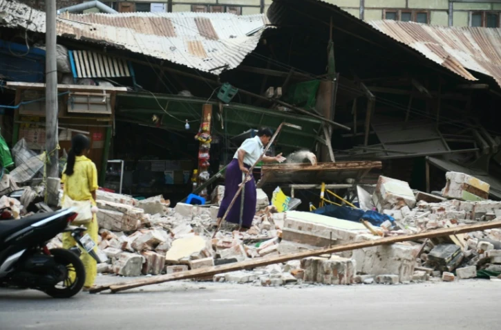 Des habitants de Mandalay, en Birmanie, nettoient les débris le 30 mars 2025 deux jours après le violent séisme