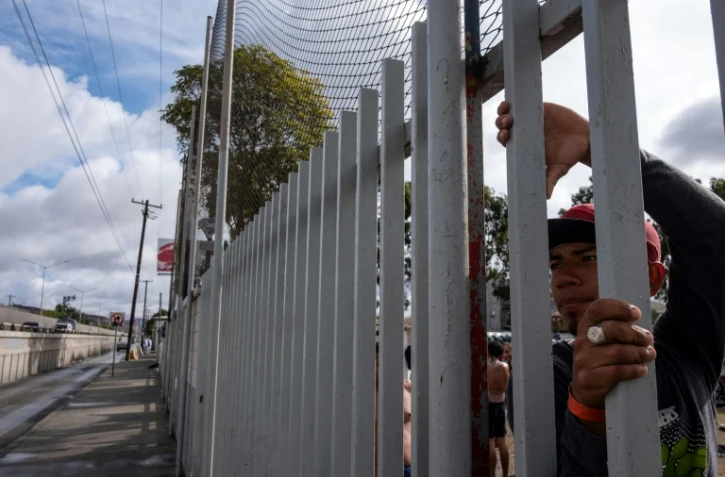 Des migrants d'Amérique centrale espérant pouvoir se rendre aux Etats-Unis regardent à travers les grilles d'un refuge situé près de la fontière américano-mexicaine, à Tijuana au Mexique, le 22 novembre 2018